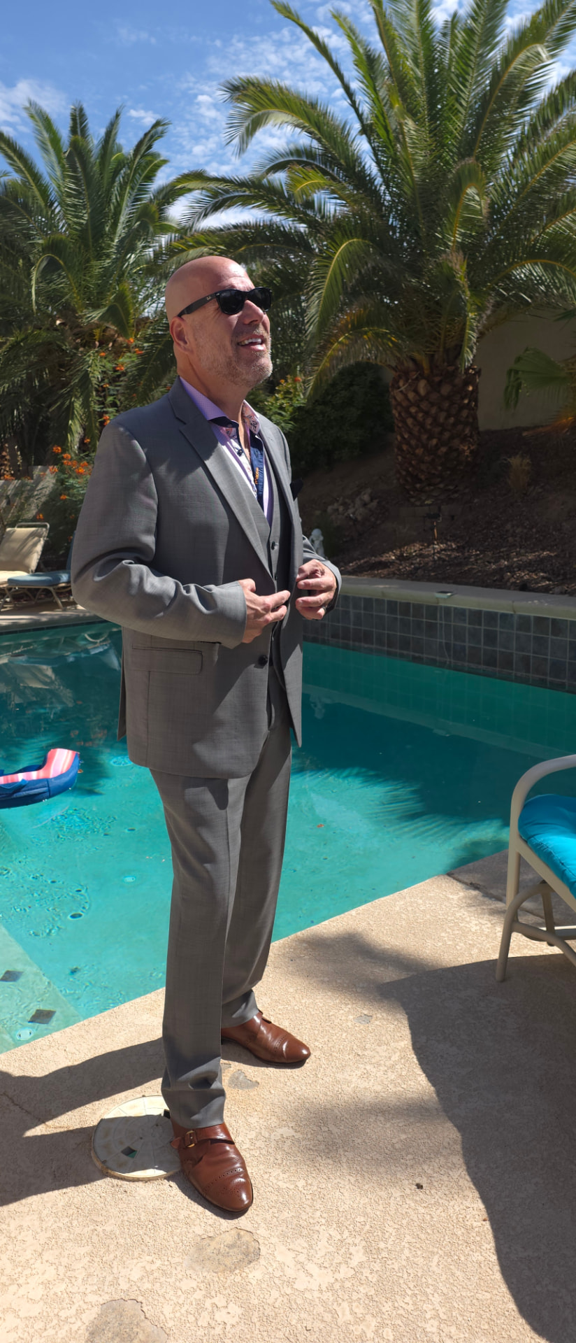 Joe smiling in a gray suit by a sunny Las Vegas pool